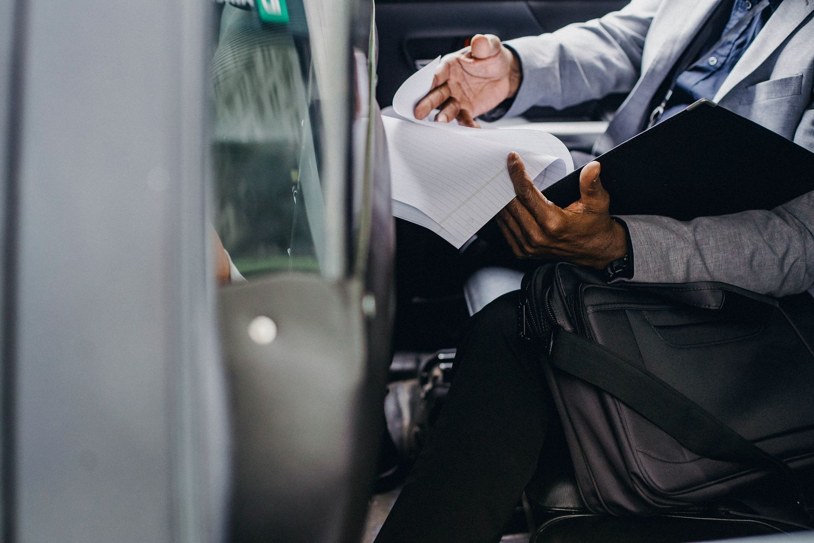 Business traveller reviewing documents in the back seat of a car