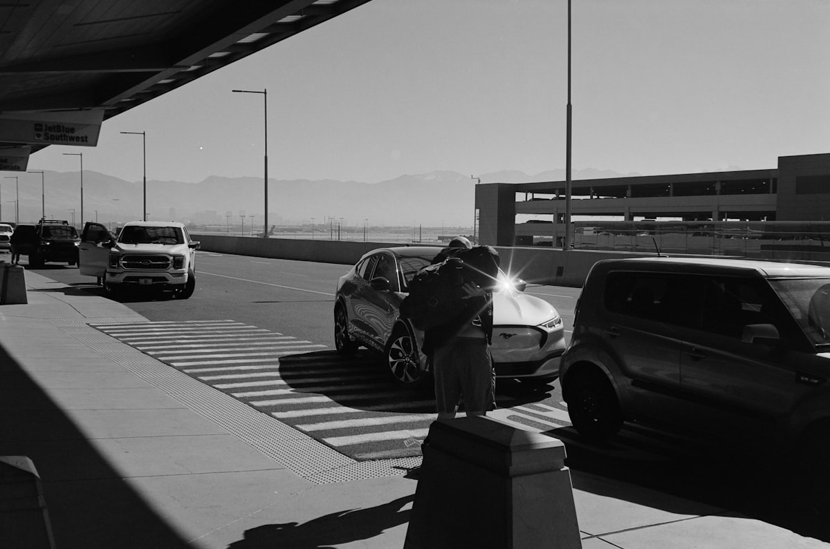 Dark full-size sedan exiting an airport return ramp