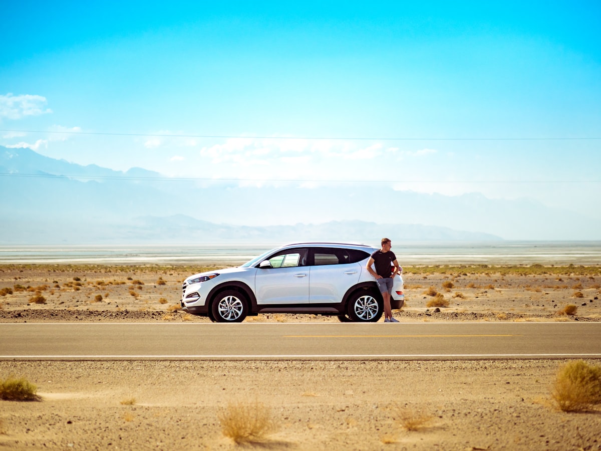 Silver SUV with tailgate open and luggage loaded on a desert highway