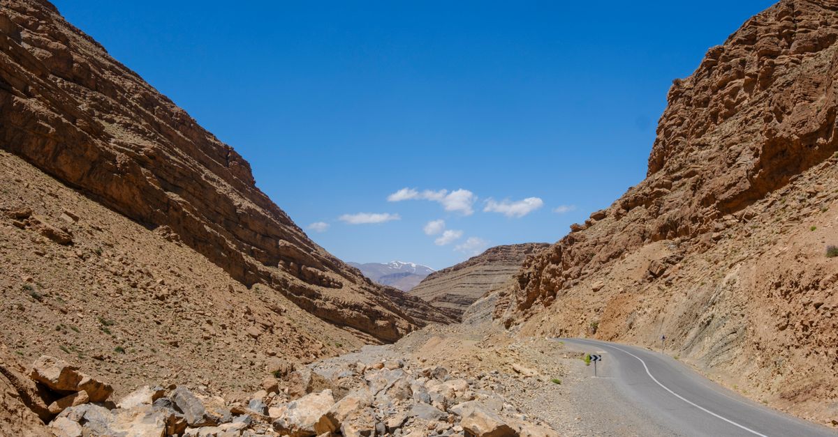 Car on a desert road in Morocco with Atlas Mountains in the background