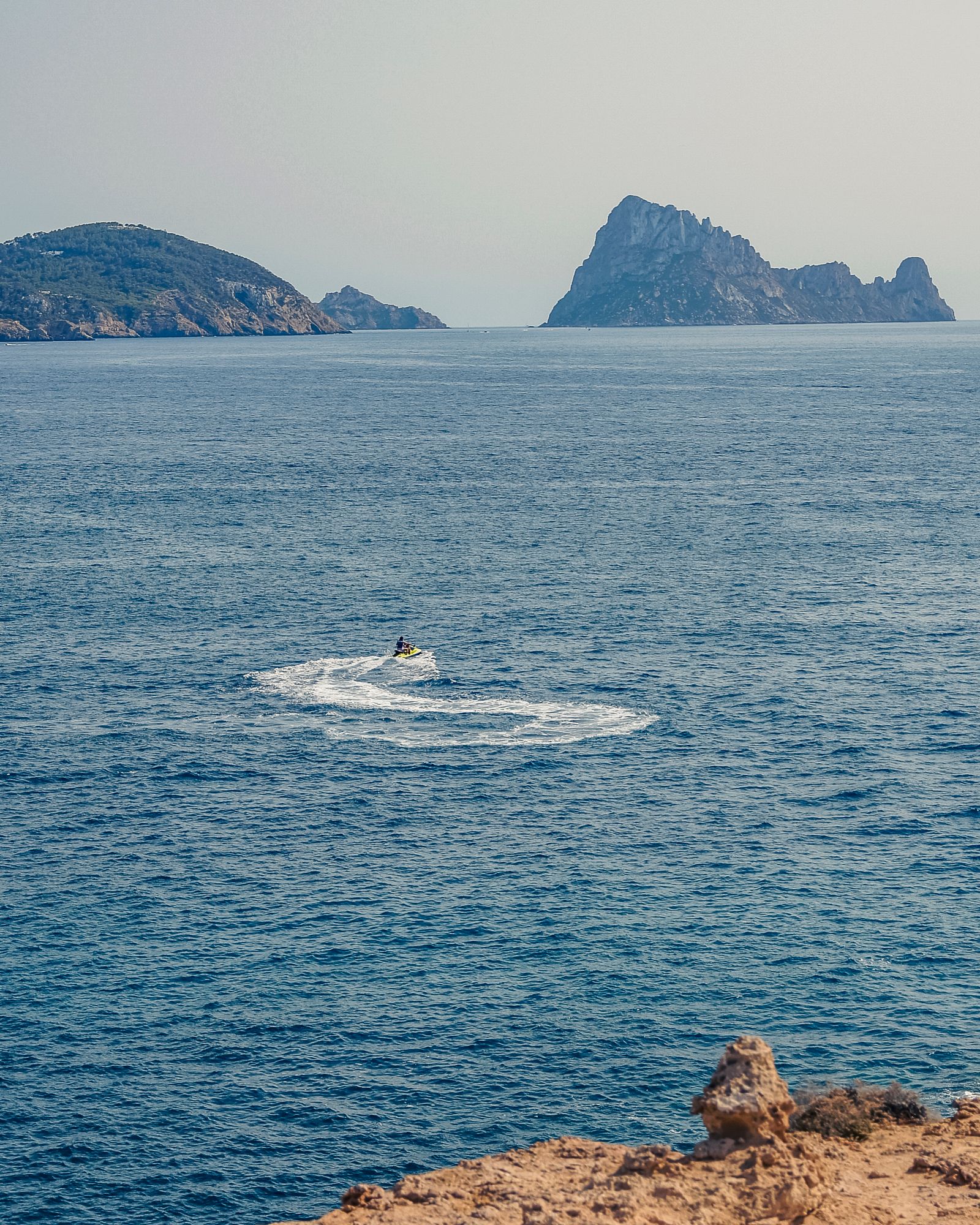 Rent a car in Ibiza: a hire car on a coastal road above Cala d'Hort with Es Vedrà in the background