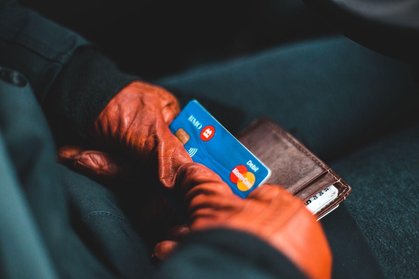 Hand holding a payment card over a card terminal at a car rental counter