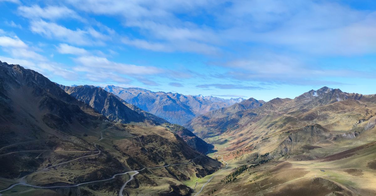 Car on a mountain road in the Pyrenees with snow-covered peaks