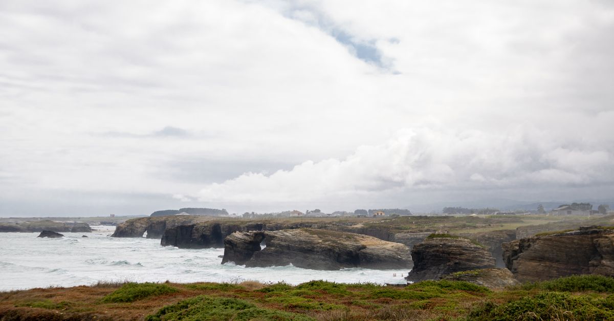 Coastal road in Galicia with green hills, ría and Atlantic Ocean